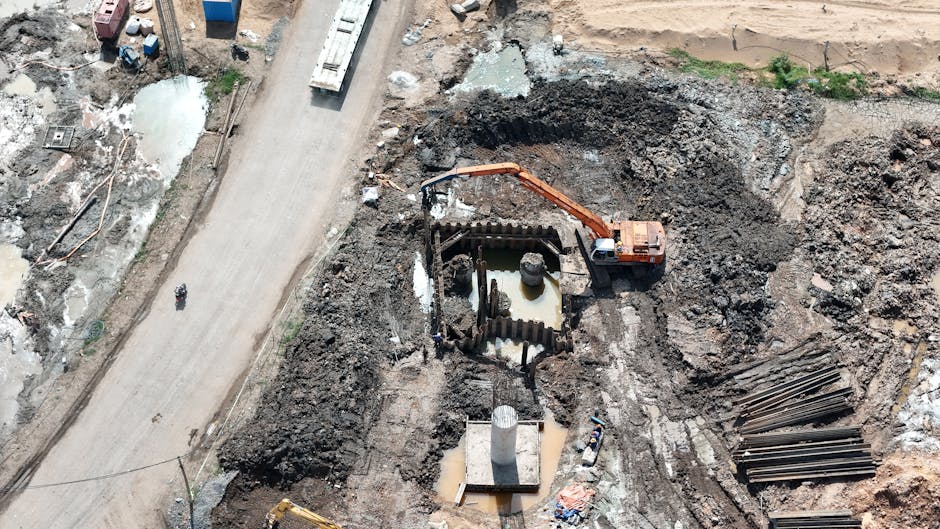 Top view of construction site showing an excavator working in muddy terrain