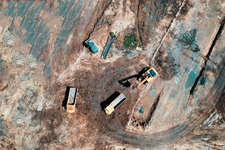 Aerial view of a construction site featuring trucks and excavation equipment in a barren landscape