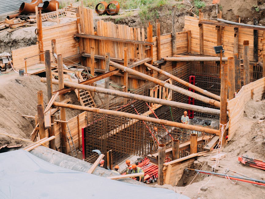 Aerial view of a construction site with workers, wooden framework, and scaffolding.