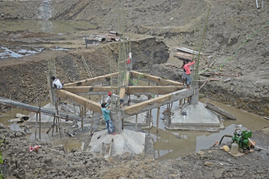 Workers constructing a building foundation with rebar and wooden supports outdoors