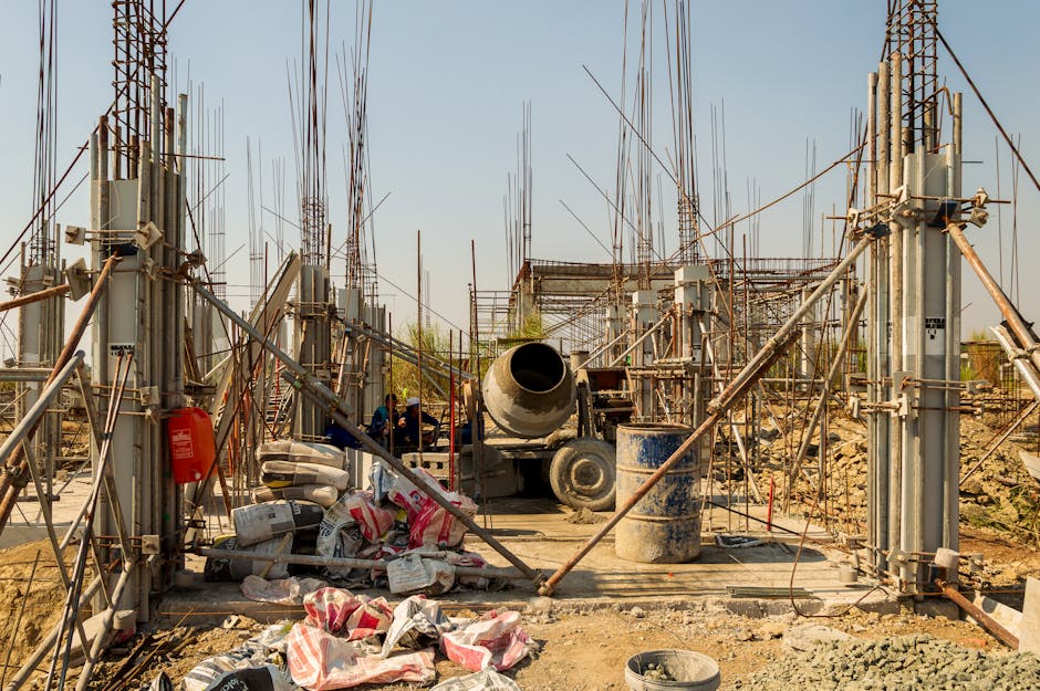 Industrial construction site featuring cement mixer, steel columns, and scaffolding in an outdoor setting
